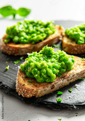 Gourmet toast, topped with smashed peas, on slate plate, isolated on white background. 