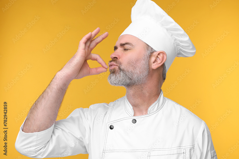 Chef in uniform showing perfect sign on orange background Chef in uniform showing perfect sign on orange background