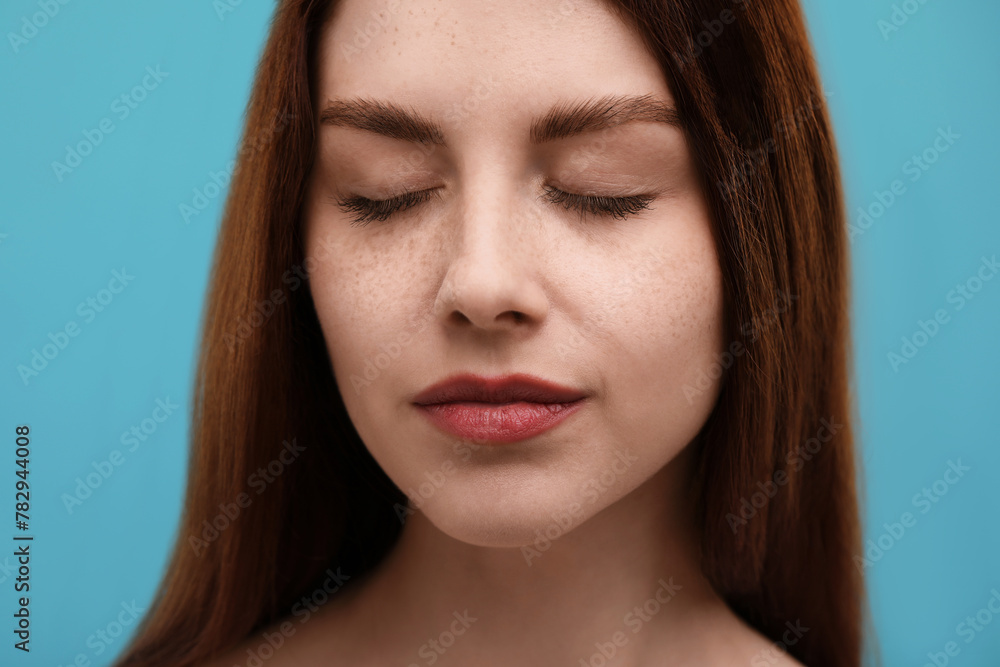 Portrait of beautiful woman with freckles on light blue background, closeup Portrait of beautiful woman with freckles on light blue background, closeup