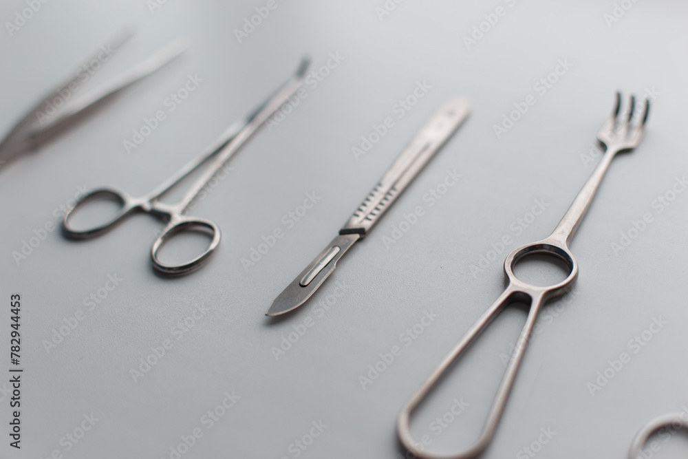 Surgical steel instrument with scalpel, scissors and clamp lie on a white background Surgical steel instrument with scalpel, scissors and clamp lie on a white background