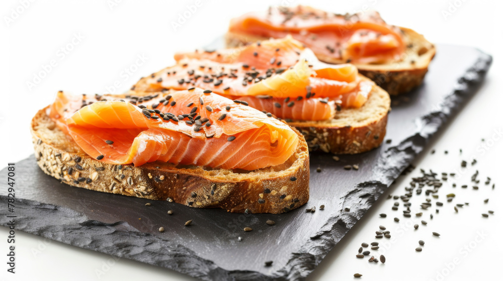 Gourmet toast, topped with smoked salmon, on slate plate, isolated on white background.
