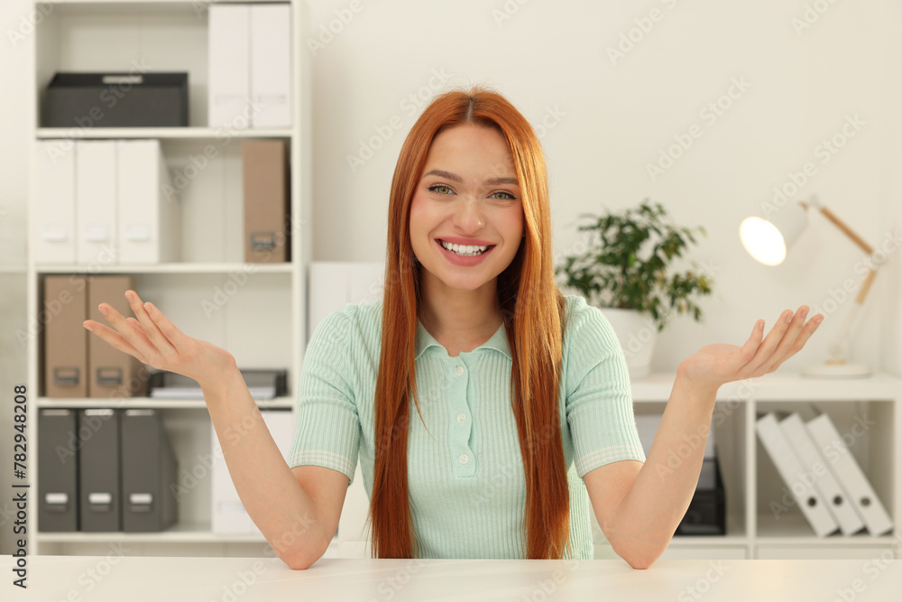 Young woman having video chat at table in office, view from web camera Young woman having video chat at table in office, view from web camera