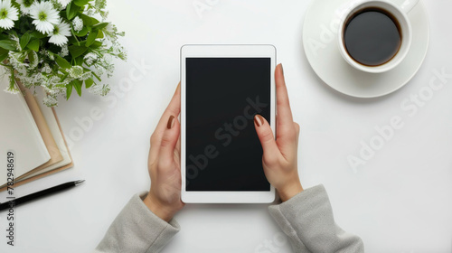 White Background. Top view image of a woman using a digital tablet at her desk close up of young female's hands on white desk. Top view of woman holding tablet.