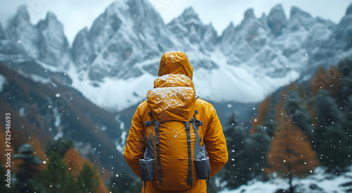 a man in a yellow jacket with snow on it looks at mountains