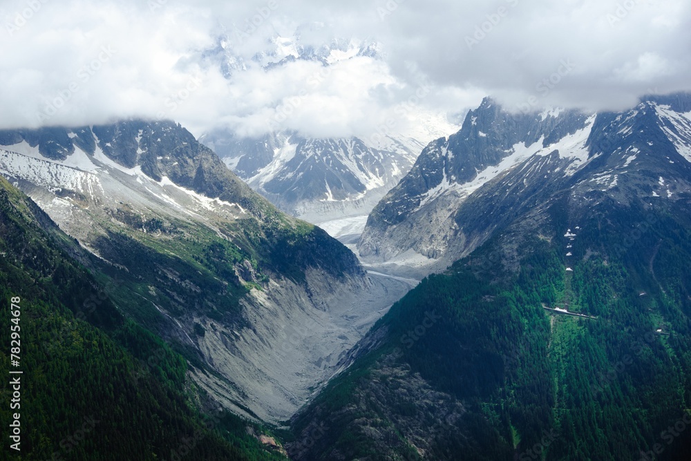 Aerial shot of the big snowy mountains with the peaks hiding behind the white clouds Aerial shot of the big snowy mountains with the peaks hiding behind the white clouds