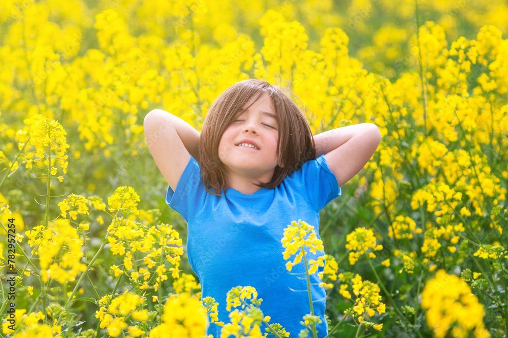 Child relaxing with his arms on his head in the middle of a rapeseed meadow on a spring day. Child relaxing with his arms on his head in the middle of a rapeseed meadow on a spring day.