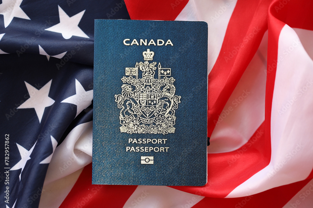 Fototapeta premium Canadian passport on United States national flag background close up. Tourism and diplomacy concept