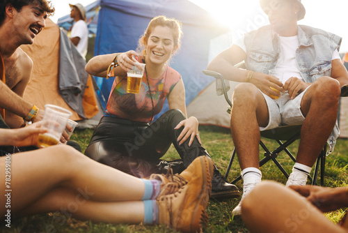Woman raising her beer cup in celebration at a festival camp with friends photo
