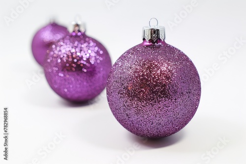 Two shiny purple Christmas ornaments on a white surface. Perfect for holiday decorations