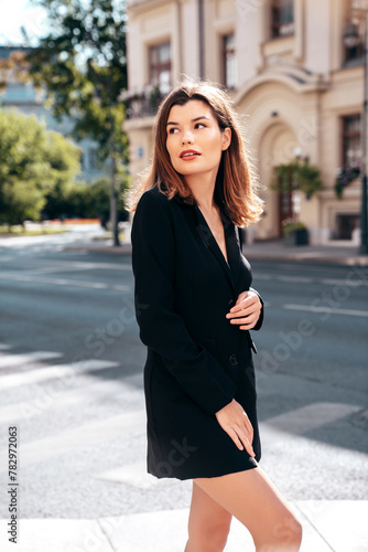 Portrait of young beautiful brunette woman wearing nice trendy suit black jacket clothes. Sexy smiling model posing in the street at sunny day. Fashionable female outdoors. Cheerful and happy