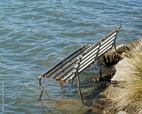 Park bench swamped by a rising sea level, New Zealand.