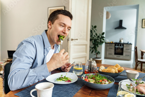 A delighted man enjoys a fresh salad at home  emphasizing the joy of healthy eating in a comfortable domestic setting.