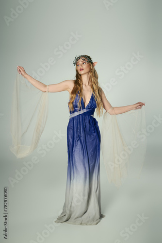 A young woman in a blue and white dress, embodying the essence of a fairy or elf princess in a dreamy, studio setting.