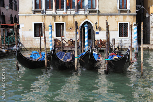 Several gondolas are moored in the canals of Venice, surrounded by picturesque medieval buildings.