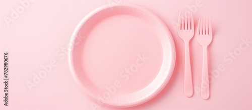 Pink plate and cutlery on pink background photo