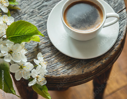 Greeting card mockup, cup of coffee. Feminine styled photo. Floral scene with blurred white cherry tree blossoms on wool taburet, stool. Wooden parquet floor. Selective photo