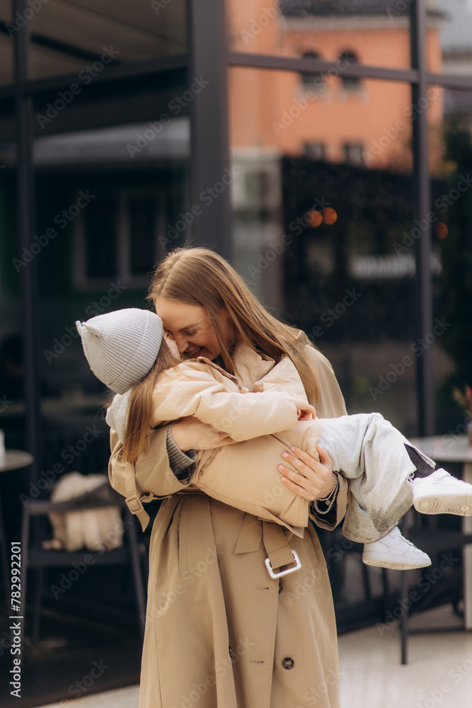 Fototapeta premium young happy mother hugs her daughter in the city