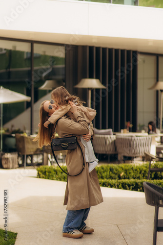 mother hugs her daughter while walking on the street
