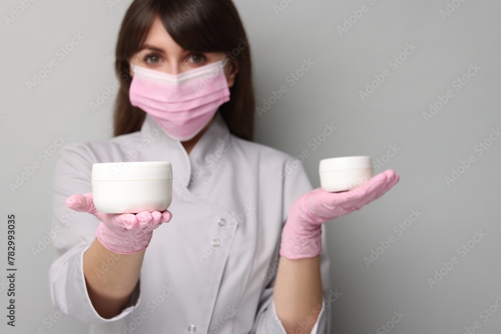 Cosmetologist with cosmetic products on grey background, selective focus Cosmetologist with cosmetic products on grey background, selective focus