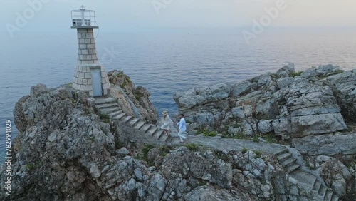 Kalamota Island, Adriatic Sea, Croatia - A Couple Making Their Way to the Lighthouse to Admire the Sunset - Aerial Pullback Shot photo
