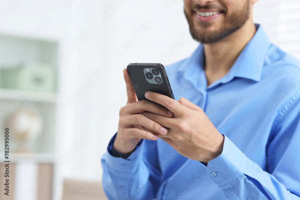 Young man using smartphone in office, closeup. Space for text Young man using smartphone in office, closeup. Space for text