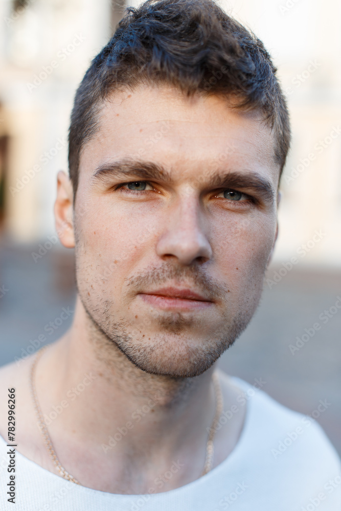 Close-up male headshot. Handsome successful man with hairstyle and beard stubble on the street