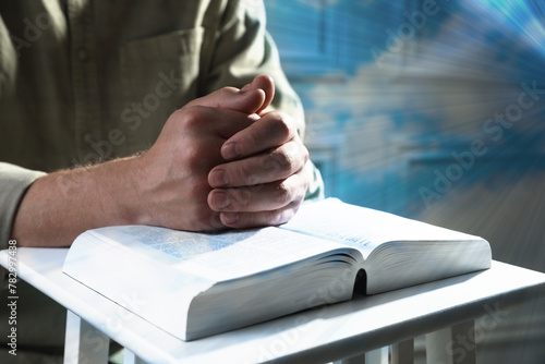 Religion. Christian man praying over Bible at table  closeup