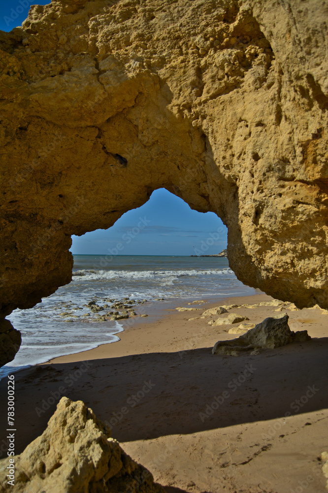 View of Portugal beach through a weathered rocky arch.