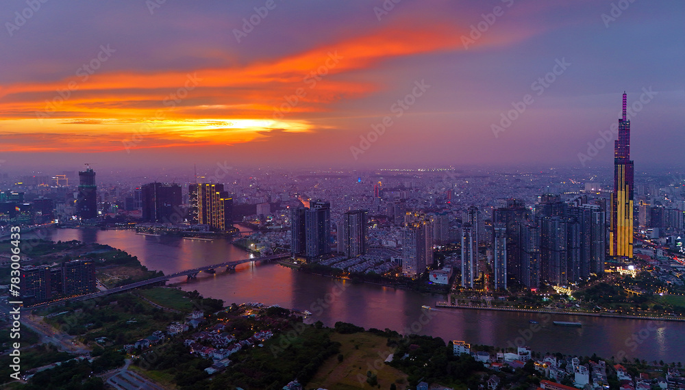 Aerial view of Asia city at sunset by drone with Landmark 81 skycraper modern building, boat on Saigon river, night skyline of Vietnam
