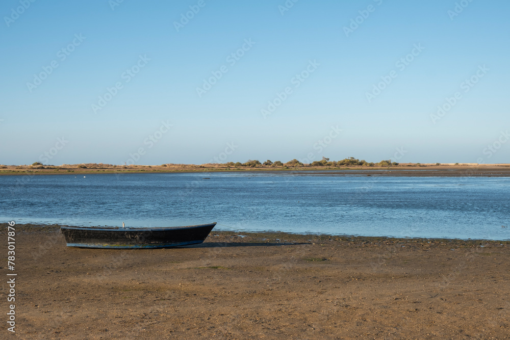 An old fishing boat rests stranded at low tide on a beach in the province of Huelva, Spain, at dawn