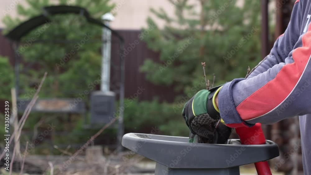 Man working in the garden, chopping branches with a garden shredder Man working in the garden, chopping branches with a garden shredder