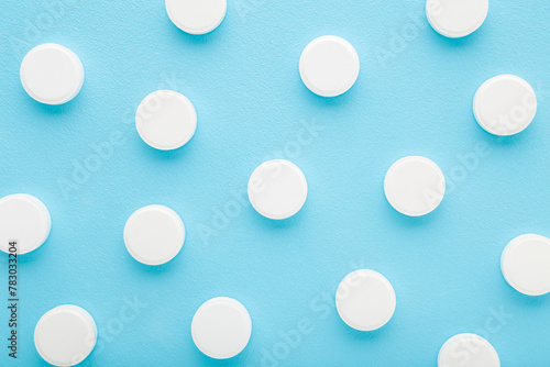 White pills of c vitamins on light blue table background. Pastel color. Closeup. Nutritional supplements pattern. Top down view.