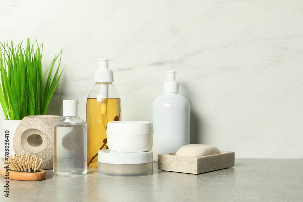 Brush and personal care products on gray table near white marble wall