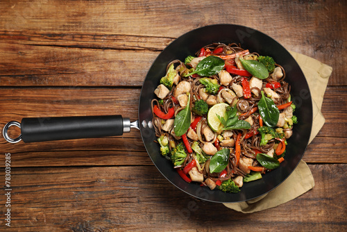 Stir-fry. Tasty noodles with meat and vegetables in wok on wooden table, top view