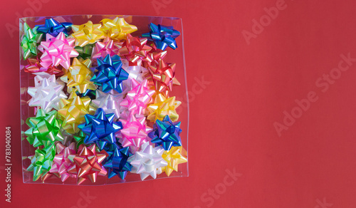Transparent box full of colorful decorations on red background. Copy space.