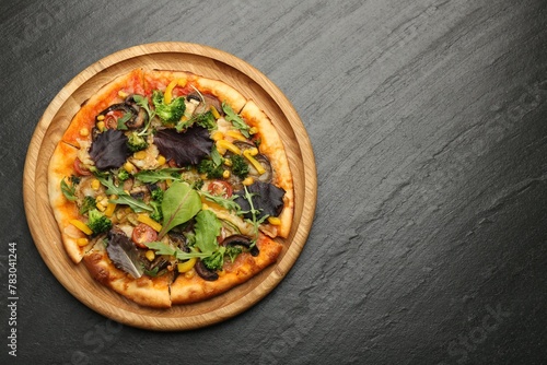 Delicious vegetarian pizza with mushrooms, vegetables and greens on black table, top view. Space for text