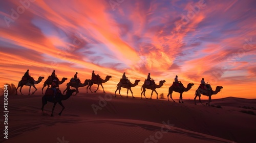 As the sun dips below the horizon  a caravan of camels and their cameleers traverse the desert sands  silhouetted against the fiery sky.