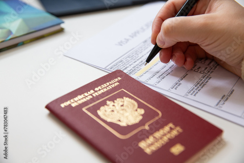 Close up of female hand filing out a visa application with a Russian passport