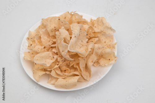 Shiitake Mushroom Crackers on white dish and grey background which consisting of shiitake mushrooms, tapioca starch, salt, ground pepper, made into sheets and then fried.