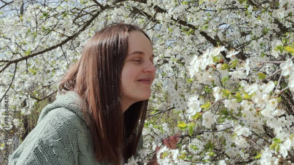 Satisfied attractive woman smelling almond blossom flower at sunny day enjoying pleasant aroma enjoying life without allergy over spring garden background Satisfied attractive woman smelling almond blossom flower at sunny day enjoying pleasant aroma enjoying life without allergy over spring garden background