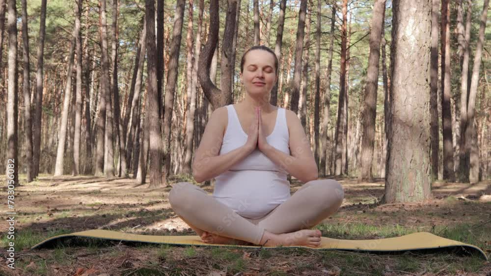 Radiant pregnant woman wearing sportswear practicing yoga nurturing her body in anticipation of motherhood sitting in lotus pose meditating in calm spring forest Radiant pregnant woman wearing sportswear practicing yoga nurturing her body in anticipation of motherhood sitting in lotus pose meditating in calm spring forest