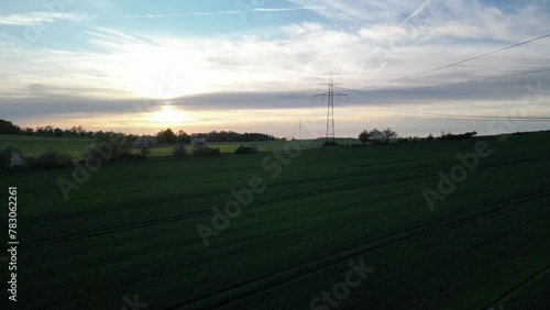 Sunset in a grain field with a high voltage power line