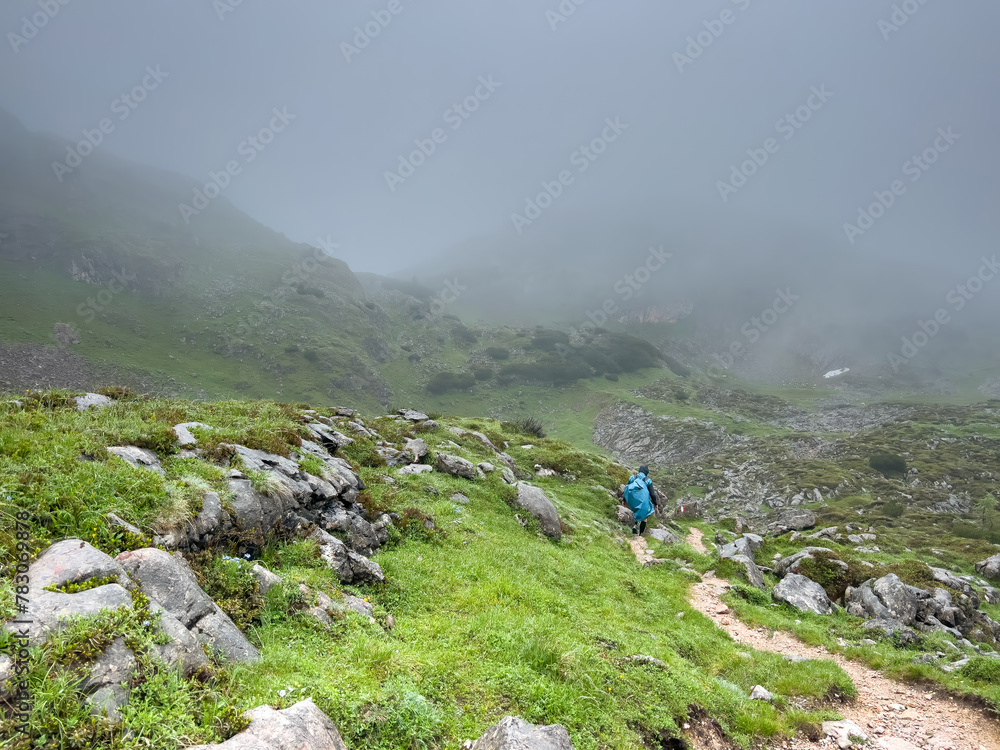 Man hike alone though the Bavarian mountains and he use a trash bag as his rain water protection Man hike alone though the Bavarian mountains and he use a trash bag as his rain water protection