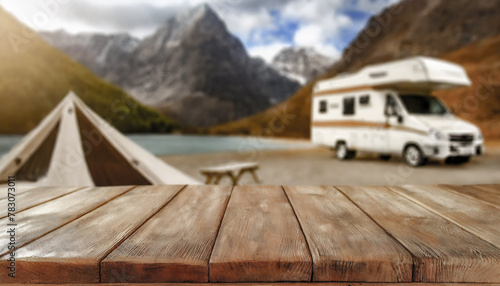 Wooden table in the tent and blurred motorhome at sunset in the mountain near the lake. Cool and relaxing concept. For product display montage or key visual layout design. space for text
 photo