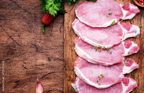 Raw pork chops on wooden board prepared for cooking with spices and pepper. Wood kitchen table background,  top view © 5ph