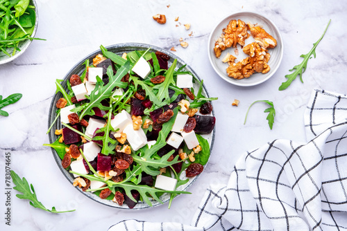 Beetroot and white cheese salad with arugula, lettuce, chard and walnuts, white table, copy space. Fresh useful vegetarian dish for healthy eating © 5ph