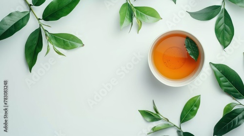 Top view shot of a hot cup of tea with green leaf decoration on white background