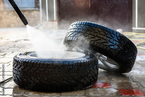 Man washing car's alloy wheels with high pressure washing. © Natallia