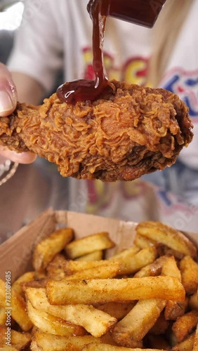 close-up of a fried chicken leg covered in sauce, slow motion video