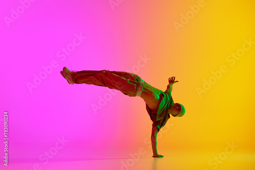 Talented break-dancer dancing in motion in neon light against gradient pink-yellow background. Concept of hobby, sport, creativity, fashion and style, motion, action. Ad
